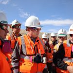 Los directores de Codelco visitan Chuquicamata y Radomiro Tomic como parte de una agenda en terreno orientada a conocer las operaciones y fortalecer la seguridad. La delegación estuvo encabezada por el presidente del directorio, Bernardo Fontaine, junto a los nuevos directores Luz Granier, Alejandro Canut de Bon y Daniel Díaz. La visita también contó con la participación del vicepresidente de operaciones (i), Lindor Quiroga, y del presidente ejecutivo, Rubén Alvarado. El recorrido incluyó reuniones con ejecutivos, trabajadores y dirigentes sindicales de ambas divisiones. Seguridad y desempeño marcaron la agenda en Chuquicamata La jornada comenzó en la División Chuquicamata. El equipo ejecutivo liderado por René Galleguillos recibió a la delegación para analizar el estado de la operación y sus principales desafíos. Durante el encuentro, los nuevos directores revisaron indicadores de desempeño y perspectivas de desarrollo. Luego recorrieron la mina subterránea y conocieron procesos vinculados al carguío, transporte y chancado norte. Revisión de controles críticos y proyectos en desarrollo La comitiva visitó además la planta de molienda, el rajo y el Proyecto Domo. En cada área observaron la implementación de controles orientados a prevenir accidentes y fortalecer la gestión de riesgos. Los directores también sostuvieron conversaciones con trabajadores y representantes sindicales. Estos encuentros permitieron recoger opiniones y conocer experiencias desde distintos niveles de la organización. “La seguridad no es sólo una prioridad declarativa, es una responsabilidad permanente que debe reflejarse en cada decisión y en cada tarea”, afirmó Bernardo Fontaine. Radomiro Tomic mostró avances en tecnología e integración operacional En la segunda jornada, los directores de Codelco visitan Chuquicamata y Radomiro Tomic para profundizar su conocimiento sobre los procesos productivos y los desafíos futuros de la Corporación. En Radomiro Tomic, el equipo ejecutivo encabezado por Claudia Domínguez presentó los principales avances de la división. La delegación recorrió instalaciones como el mirador mina, la rotopala, el Proyecto Lixiviación Clorurada y la zona de pilado. Centro Integrado de Operaciones destaca por su aporte tecnológico Uno de los puntos más relevantes fue la visita al Centro Integrado de Operaciones (CIO). Allí conocieron herramientas que permiten optimizar la gestión y coordinar procesos en tiempo real. Los nuevos directores valoraron especialmente el uso de tecnología para mejorar la eficiencia y apoyar la toma de decisiones. Además, destacaron la importancia de integrar procesos para enfrentar los desafíos de la minería moderna. Agenda estratégica para fortalecer el vínculo con las divisiones Las actividades concluyeron con reuniones junto a dirigentes sindicales y equipos ejecutivos. Estas instancias permitieron intercambiar visiones sobre los desafíos operacionales y el futuro de la empresa. Según Fontaine, las visitas en terreno ayudan a comprender mejor la realidad de las operaciones y fortalecen una cultura basada en la responsabilidad compartida. Con este despliegue, el directorio busca consolidar una gestión alineada con cuatro pilares estratégicos. Estos son la seguridad, el aumento de aportes al Estado sin elevar la deuda, la transparencia institucional y la sostenibilidad operacional, económica, ambiental y social de Codelco.